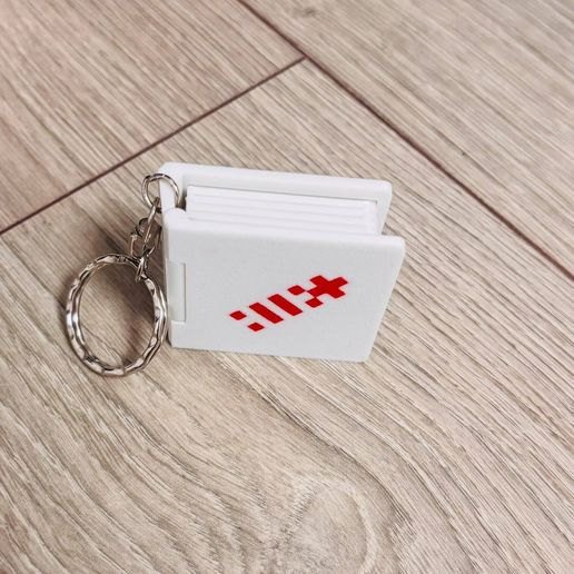 Closed white book keychain on a wooden floor